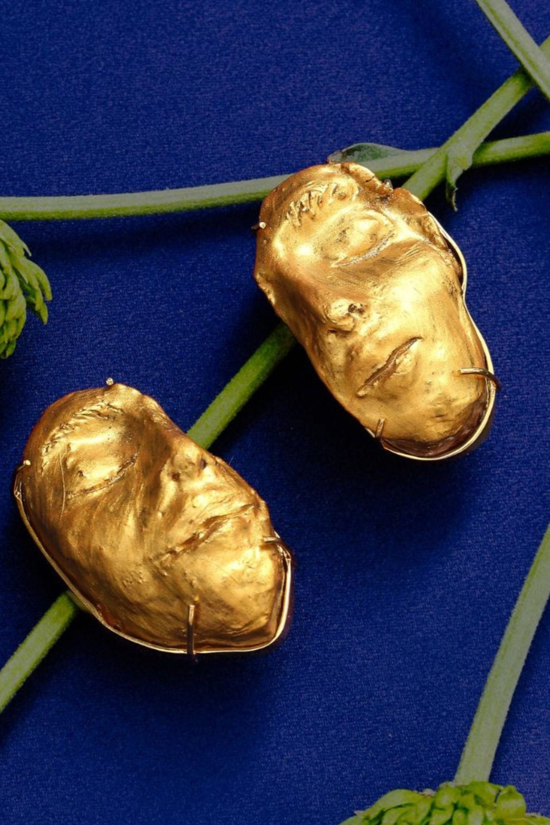 Gold-plated earrings designed to resemble human faces