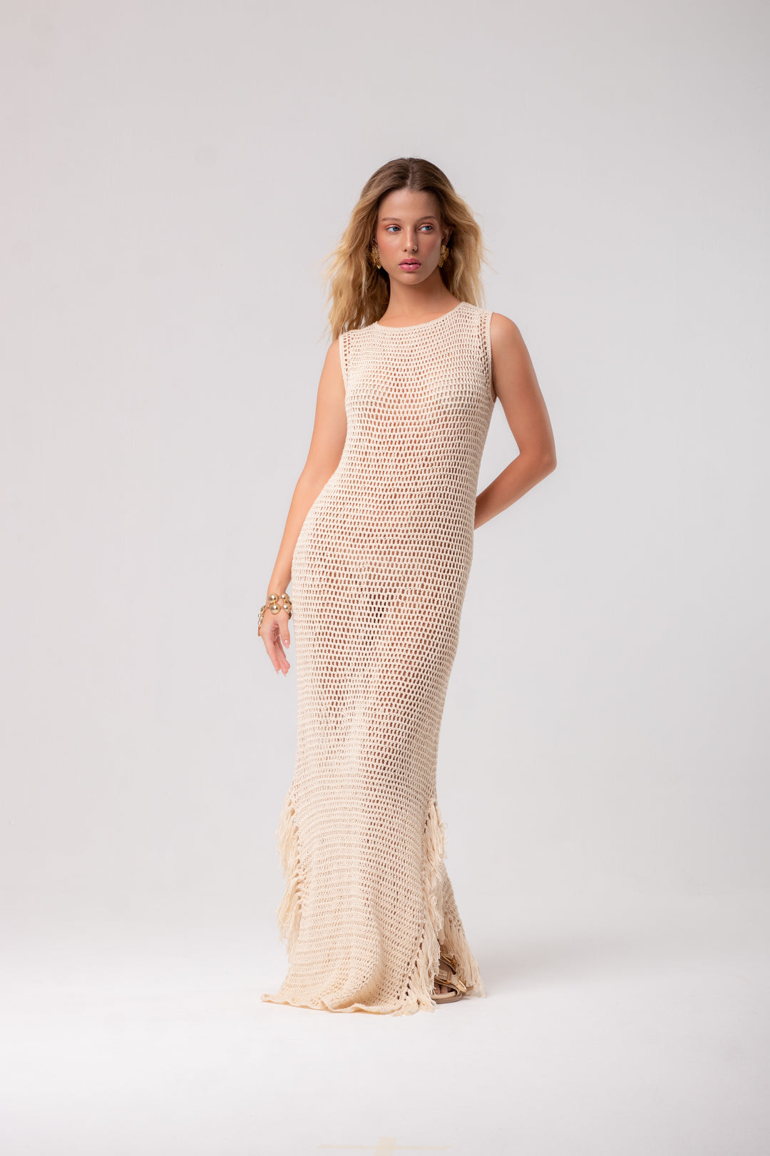 an off-white, long, sleeveless crochet dress.