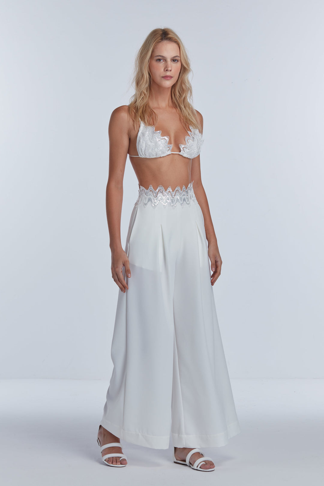 off-white sequin tailored pants with a matching sequin top. The outfit is designed with a side closure and an invisible zipper, presenting a blend of tailoring and sequin embroidery.