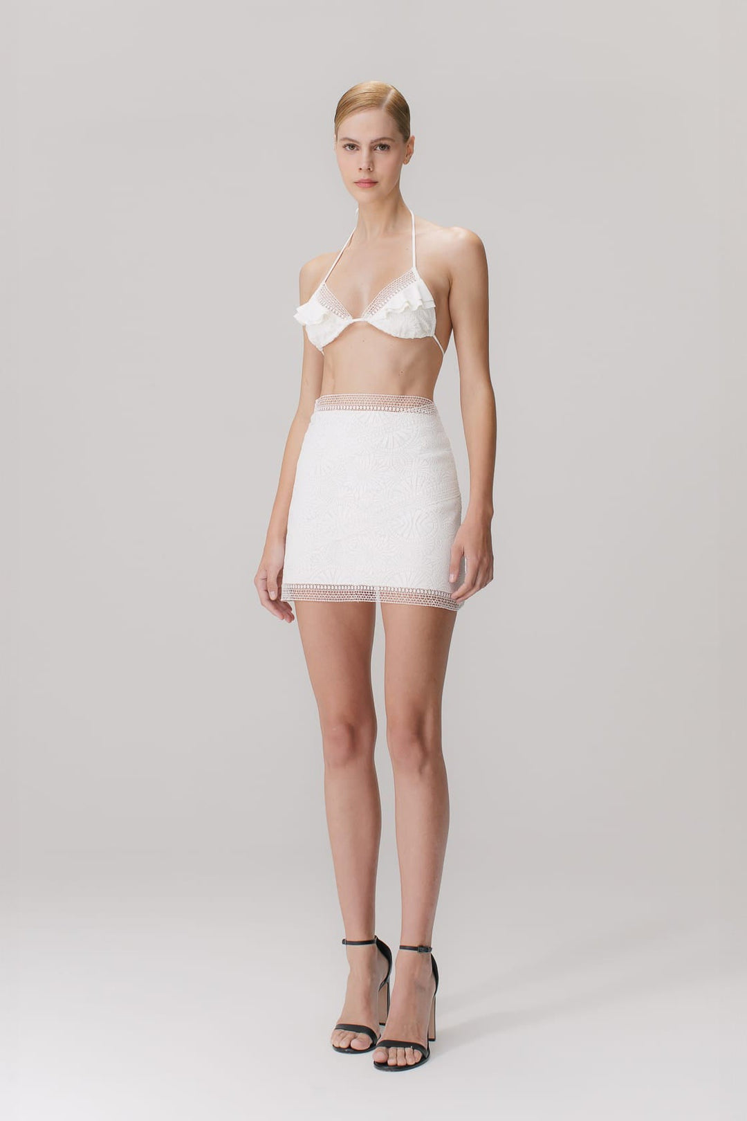 A short skirt with mandala guipure appliqués in off white color, featuring a high-waisted design and a side closure with an invisible zipper.