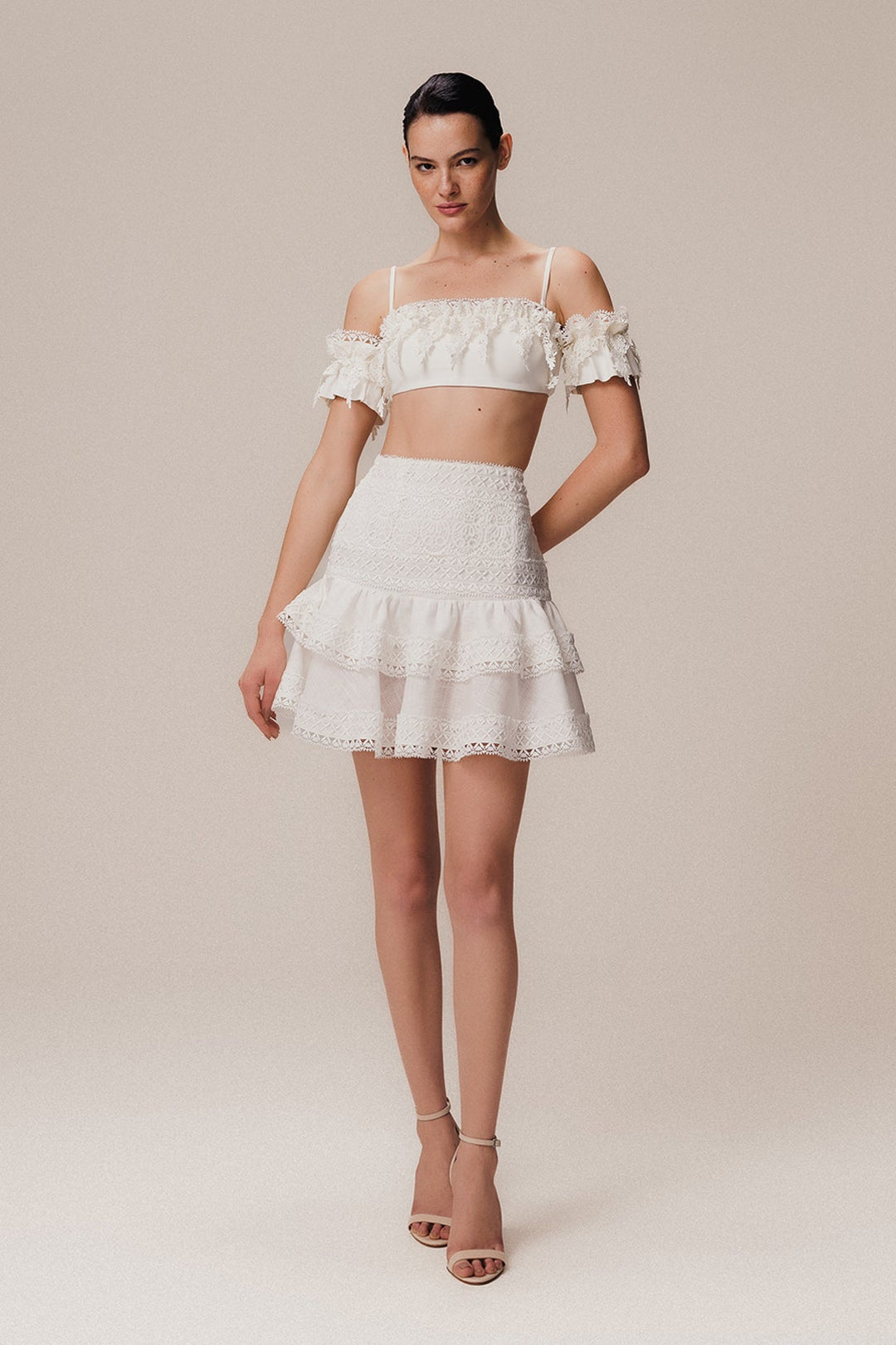 An off-shoulder top and a short ruffled linen skirt off white