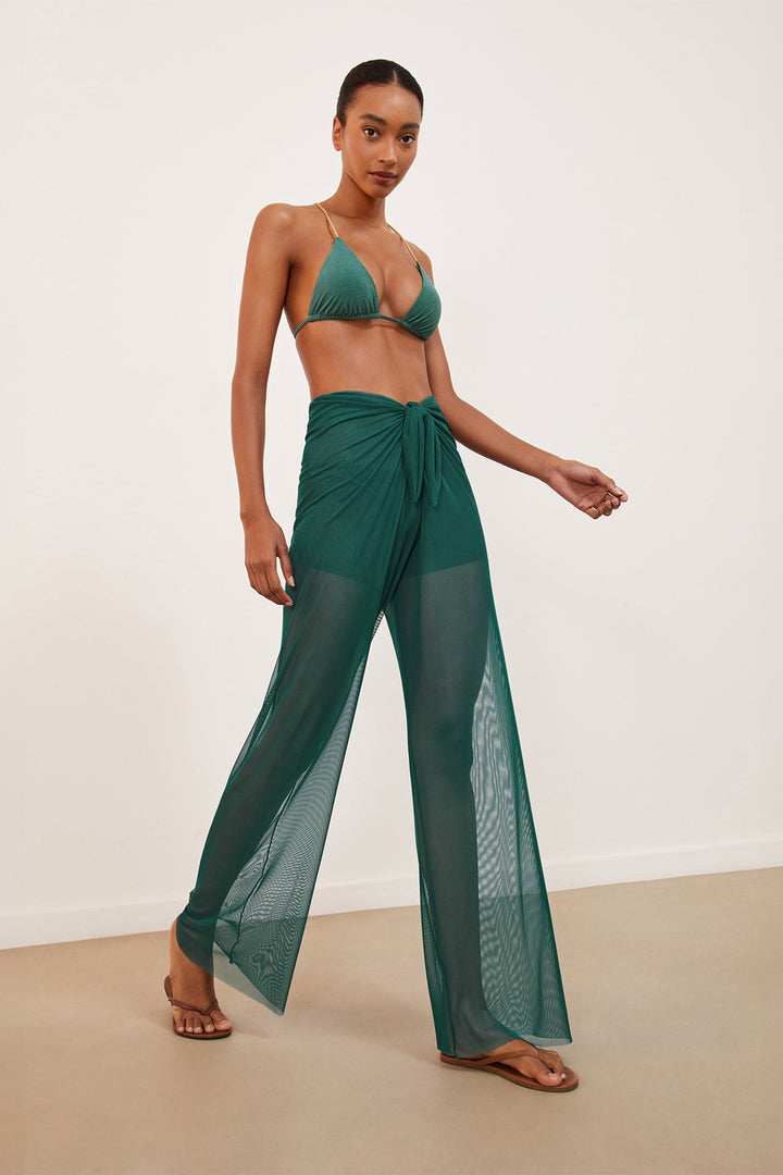 A model wearing green flowy tulle pareo pants with a front knot, paired with a bikini top.