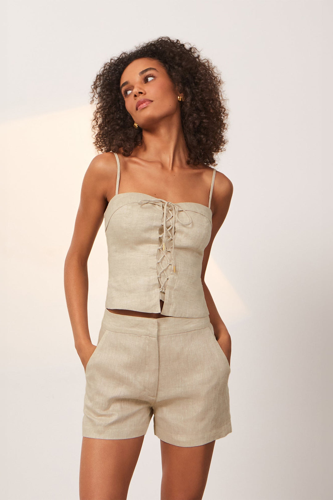 A natural color linen top with a unique lace-up detail and gold accents