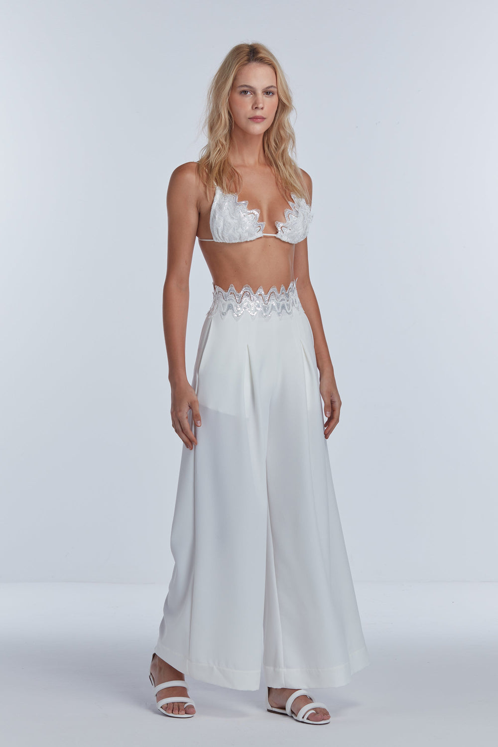 off-white sequin tailored pants with a matching sequin top. The outfit is designed with a side closure and an invisible zipper, presenting a blend of tailoring and sequin embroidery.